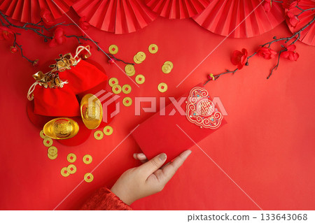 Lunar New Year celebration with red envelope and gold ingots on red background 133643068