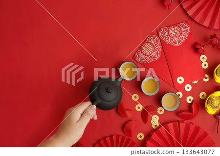 Pouring tea for Lunar New Year celebration with red envelopes Pouring tea for Lunar New Year celebration with red envelopes 133643077