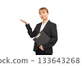 A woman in a business suit posing as if saying "please" 133643268