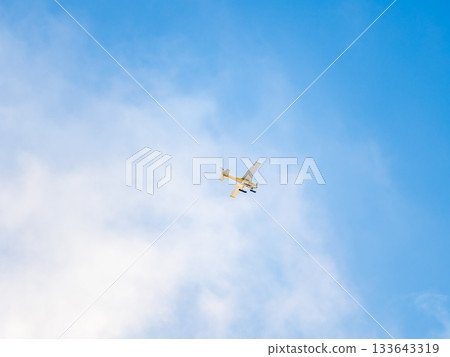 Small ultralight airplane with overhead wing and single propeller flying in sunset sky. Small ultralight airplane with overhead wing and single propeller flying in sunset sky. 133643319