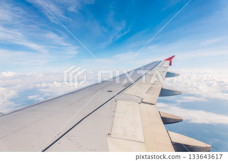 View from the airplane window at a beautiful cloudy sky and the airplane wing View from the airplane window at a beautiful cloudy sky and the airplane wing 133643617
