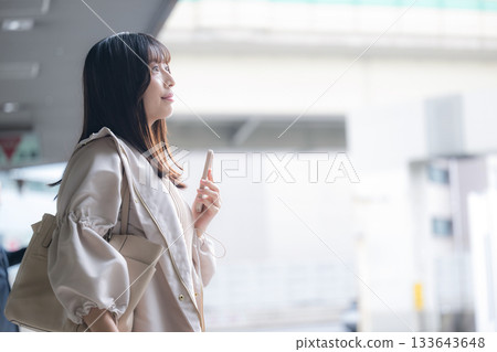 一位女士在機場或交通樞紐手持智慧型手機的照片。旅行和度假圖片。個人資料。 133643648