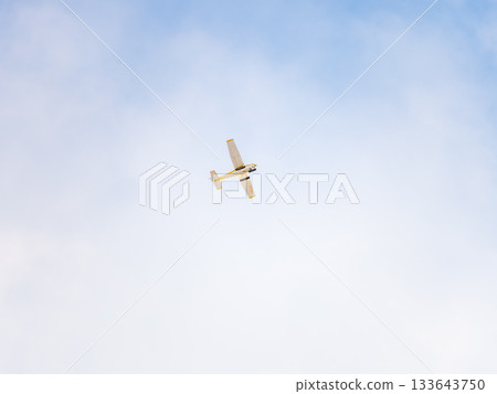 Small ultralight airplane with overhead wing and single propeller flying in sunset sky. 133643750