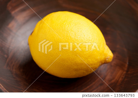 Whole citrus fruit lemon in a wooden bowl close up Whole citrus fruit lemon in a wooden bowl close up 133643793