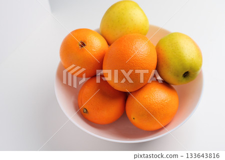 Fresh citrus fruits and green yellow seasonal apples in a white ceramic bowl 133643816