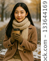 雪地裡，一位女子手持熱飲 133644169