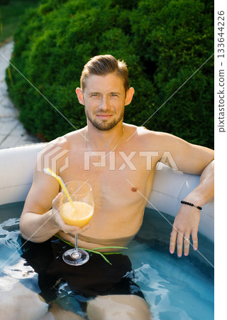 Man Relaxing In Pool With Orange Drink Man Relaxing In Pool With Orange Drink 133644226