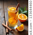Homemade spiced orange infused water or cocktail with cinnamon sticks, served in a tall glass on a rustic dark wood table. Homemade spiced orange infused water or cocktail with cinnamon sticks, served in a tall glass on a rustic dark wood table. 133644460