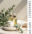 Elevated skincare set with glass dropper bottles, white cream jar, and jade massage tool in soft morning light with eucalyptus accents. Elevated skincare set with glass dropper bottles, white cream jar, and jade massage tool in soft morning light with eucalyptus accents. 133644465