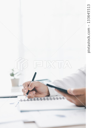 Businessman reviews financial reports, points on chart with pen while analyzing data at office desk working with calculator for accuracy. Concept of accounting, business planning, investment strategy. 133645513