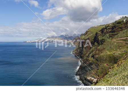 Madeira Atlantic coast near Garajau with steep green cliffs and distant white Funchal views 133646346