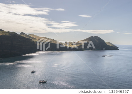 Golden morning light over Ponta de Sao Lourenco cliffs with sailboats on calm Atlantic waters Golden morning light over Ponta de Sao Lourenco cliffs with sailboats on calm Atlantic waters 133646367
