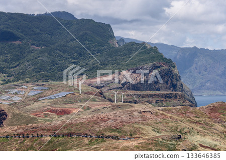 Madeira coast with green mountain slopes wind turbines solar panels and layered rocky terrain 133646385