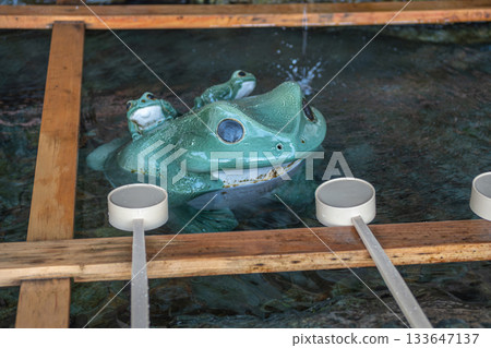 Ceramic frog water fountain with ladles in wooden frame basin near Meoto Iwa Futami, Ise city, Japan 133647137