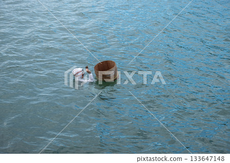 Ama Divers of Ise Shima fishing tradition in Mie Prefecture, Japan Person swimming in water with wooden barrel floating nearby 133647148
