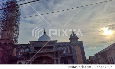 Mosque dome and minaret construction under sunset sky 133647206