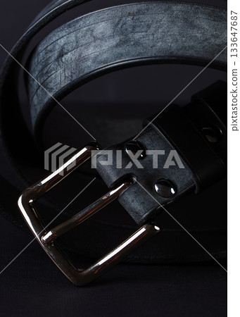 A black belt with a gold buckle. The buckle is on the left side of the belt 133647687