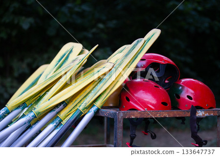 Boat oars and red helmets for rafting. Active recreation during the trip Boat oars and red helmets for rafting. Active recreation during the trip 133647737