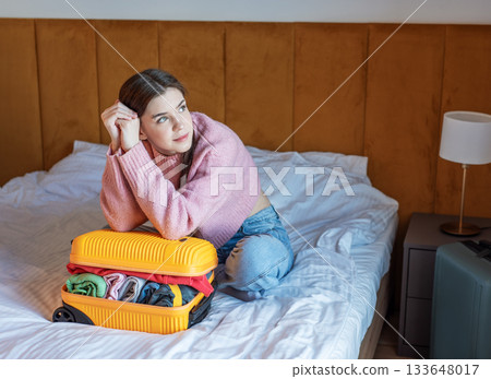 Woman dreaming about travel while packing suitcase on bed 133648017