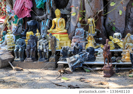 A crumbling and broken Buddha statue with golden figures at an outdoor Buddhist shrine. A crumbling and broken Buddha statue with golden figures at an outdoor Buddhist shrine. 133648110