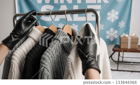 Gloved Hands Browsing Winter Sweaters Under WINTER SALE Banner 133648368