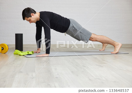 Man doing strength training on gray mat, focusing on core muscles Man doing strength training on gray mat, focusing on core muscles 133648537