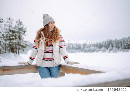 Beautiful young woman in winter clothes enjoying the winter forest. Christmas. 133648921