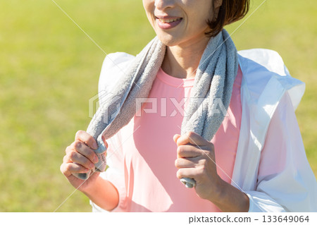 Middle-aged woman wiping sweat with a towel after exercising outdoors Middle-aged woman wiping sweat with a towel after exercising outdoors 133649064