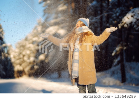 Young woman in warm clothes plays with snow on a sunny winter day. Concept of walking, fun. 133649289