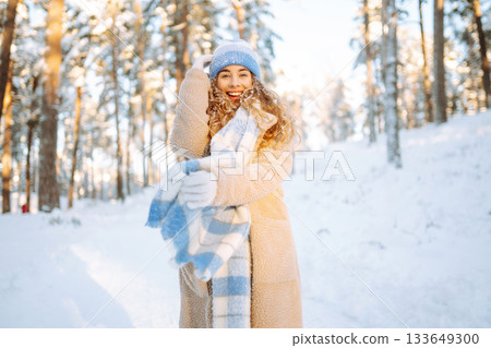 Young woman in warm clothes plays with snow on a sunny winter day. Concept of walking, fun. Young woman in warm clothes plays with snow on a sunny winter day. Concept of walking, fun. 133649300