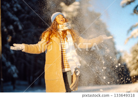 Young woman in warm clothes plays with snow on a sunny winter day. Concept of walking, fun. 133649318