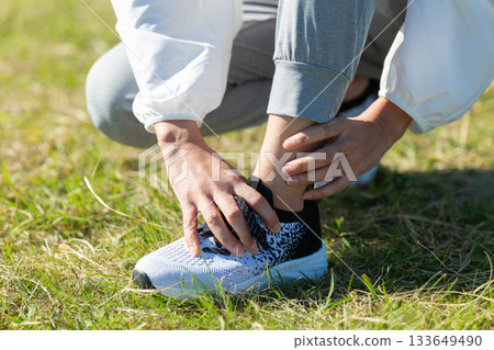 中年婦女在戶外運動時扭傷了腳踝。 中年婦女在戶外運動時扭傷了腳踝。 133649490