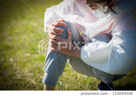 Middle-aged woman hurting her knee while exercising outdoors 133649506