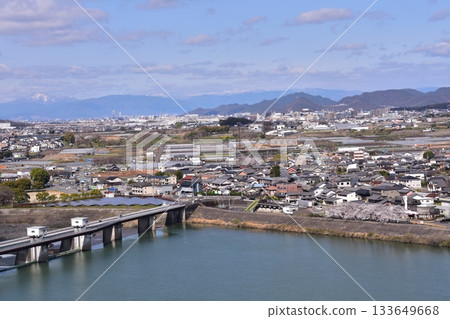 Inuyama City, Aichi Prefecture, Japan: Inuyama Castle in spring and cherry blossoms in full bloom. View from the top floor of the national treasure castle tower, the surrounding cityscape and nature. 133649668