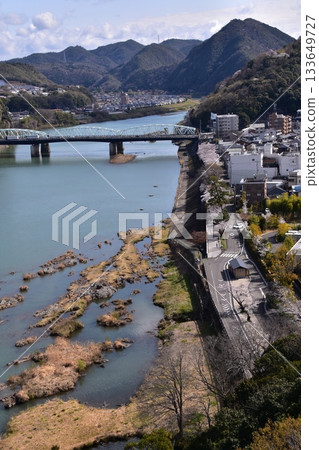 Inuyama City, Aichi Prefecture, Japan: Inuyama Castle in spring and cherry blossoms in full bloom. View from the top floor of the national treasure castle tower, the surrounding cityscape and nature. Inuyama City, Aichi Prefecture, Japan: Inuyama Castle in spring and cherry blossoms in full bloom. View from the top floor of the national treasure castle tower, the surrounding cityscape and nature. 133649727