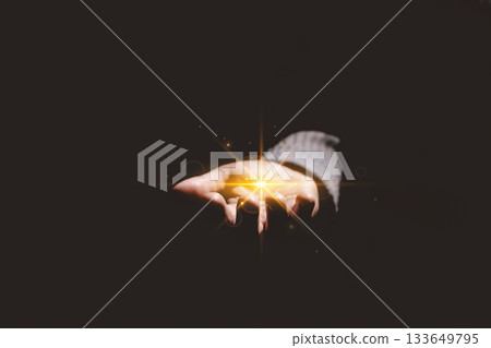 Hands holding glowing light, symbolizing hope, healing, faith, inspiration, spiritual energy, new beginning, miracle, inner strength and positive transformation from darkness to light. 133649795