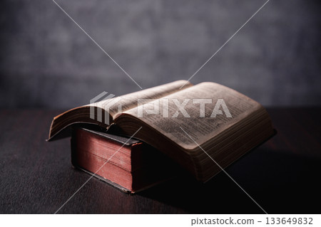 Open Bible on black background. Religion concept. a Christian sat reading an open Bible the holy book of Christianity deepening their faith in God and Jesus Christ, the foundation of their religion. Open Bible on black background. Religion concept. a Christian sat reading an open Bible the holy book of Christianity deepening their faith in God and Jesus Christ, the foundation of their religion. 133649832