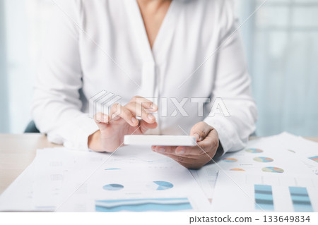 Close up of businesswoman using calculator for financial analysis and accounting on office desk with charts and reports. Concept of business planning, budget calculation and investment strategy. Close up of businesswoman using calculator for financial analysis and accounting on office desk with charts and reports. Concept of business planning, budget calculation and investment strategy. 133649834