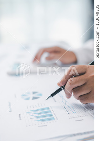 Concept of financial planning and accounting. A businesswoman uses a calculator to analyze reports and charts, calculating budget and investment strategy with focus and precision at office desk. 133649835