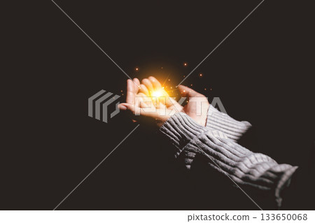 Hands holding glowing light, symbolizing hope, healing, faith, inspiration, spiritual energy, new beginning, miracle, inner strength and positive transformation from darkness to light. 133650068