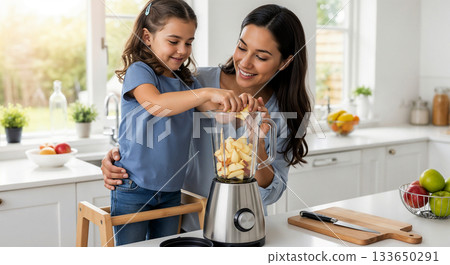 A mother and daughter are making an apple smoothie together using a blender. A mother and daughter are making an apple smoothie together using a blender. 133650291