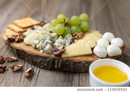 Gourmet cheese board with grapes and crackers on rustic wood background 133650583