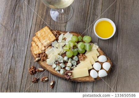 Elegant cheese and wine pairing with grapes, crackers, and walnuts on rustic wood 133650586