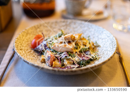 Fresh caesar salad with grilled chicken and cherry tomatoes in rustic ceramic bowl 133650590