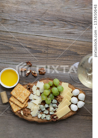 Elegant cheese and wine pairing with grapes, crackers, and walnuts on rustic wood Elegant cheese and wine pairing with grapes, crackers, and walnuts on rustic wood 133650648