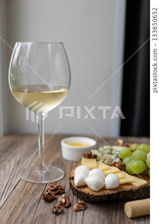 Elegant wine and cheese board with grapes and nuts on rustic wooden table 133650652