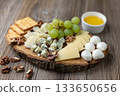 Gourmet cheese board with grapes and crackers on rustic wood background 133650656