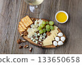 Elegant cheese and wine pairing with grapes, crackers, and walnuts on rustic wood 133650658