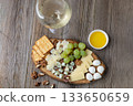 Elegant cheese and wine pairing with grapes, crackers, and walnuts on rustic wood 133650659