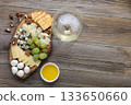 Elegant cheese and wine pairing with grapes, crackers, and walnuts on rustic wood 133650660